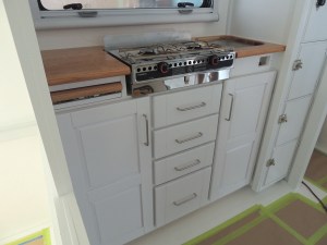 Kitchen lower cabinet installation sequence-heat shield for stove, stove, slide out cutting board, drawers, doors, sink